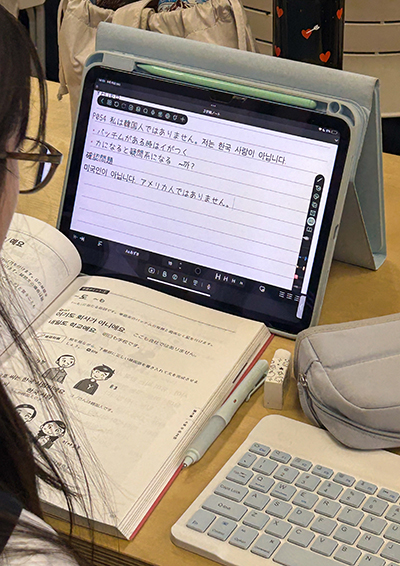 韓国研修に向けて、タブレットや教材を活用して韓国語を学ぶ生徒
