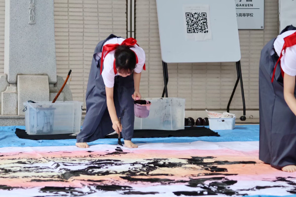 床に置かれた大きな紙に音楽に合わせて字を書いていく、桜鏡祭の書道パフォーマンス