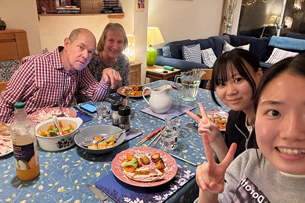 ホストファミリーと食卓を囲み、楽しそうな様子の H.K.さん