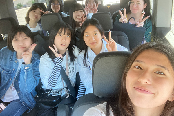 修学旅行の車内で、たくさんの友達と一緒に笑顔を見せるM.P.さん