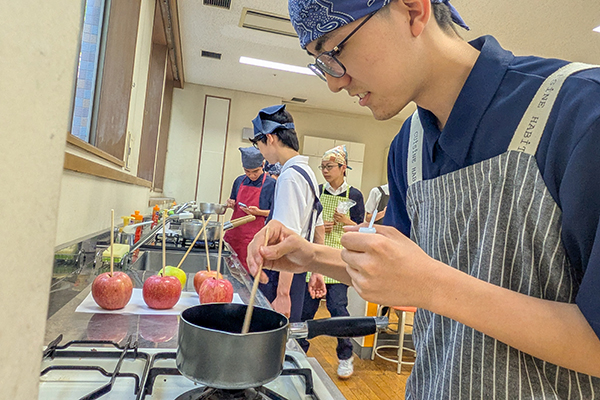 調理室でエプロンやバンダナを装着し、りんご飴づくりに取り組む生徒たち