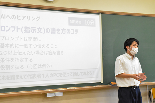 黒板に投影されたプロジェクター画面で「AIへのプロンプト」のコツを解説し、プレゼンを行う生徒