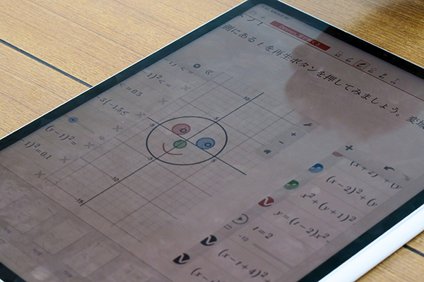 iPad画面に「Desmos」が映し出されている。式を入力し、円グラフで顔を作成
