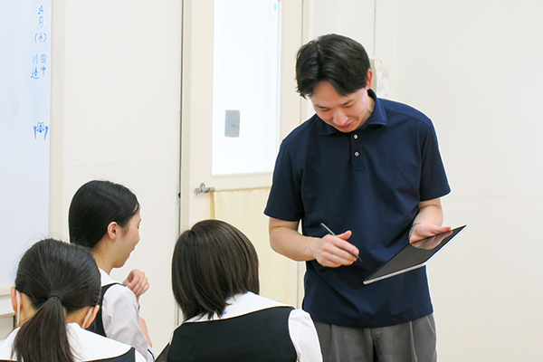 iPadを持って、教室を回りながら質問に答える坂本先生