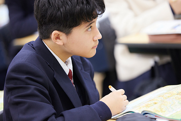 集中した様子でメモを取りながら授業を聞く男子学生