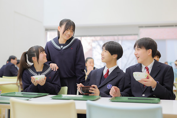 カフェテリアで食事をとりながら談笑する4名の生徒たち