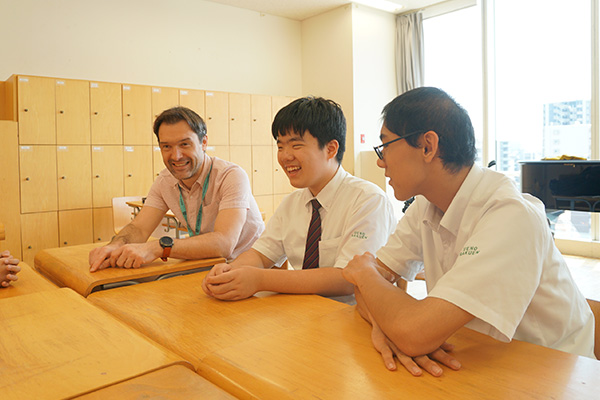 明るく話すロブ先生と、楽しそうに話を聞く男子生徒2名