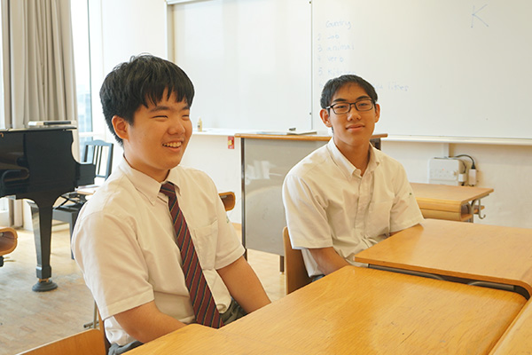 明るく日の差し込む教室で、対談を行う男子生徒2名