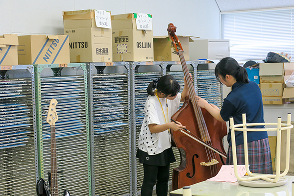 吹奏楽部の体験企画で先輩からコントラバスの弾き方を教わる参加者