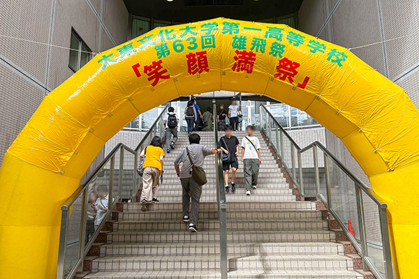 2025年度雄飛祭の様子。2025年度のテーマ「笑顔満祭」と大きく書かれた枠をくぐる来場者たち