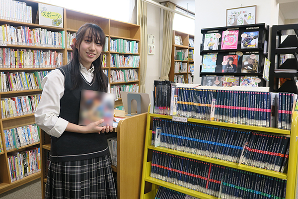 語で書かれたコミックスを手に取り、洋書コーナーを紹介する西脇さん