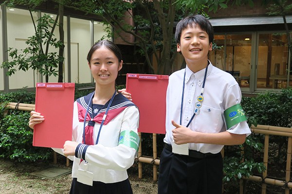 Student Ambassadorの腕章をつけたSAの2人が校内を案内する様子