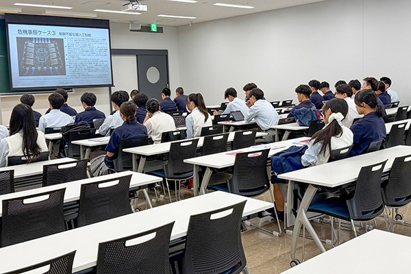危機管理学部を訪問した生徒たち。スクリーンに映し出される専門的な講義を受けている