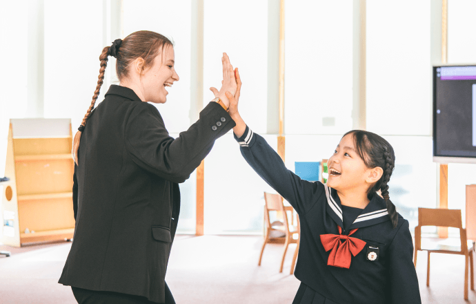 女子児童とネイティブ教員が笑顔でハイタッチしている様子