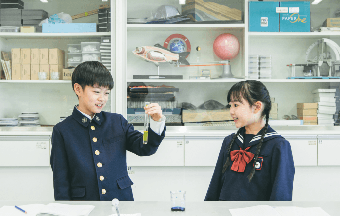 理科実験室で試験管を持つ男子児童とそれを見ている女子児童