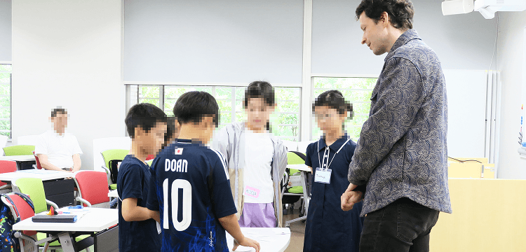 ドイツ語ミニレッスンでカードゲームをする藤澤先生と子どもたちの写真
