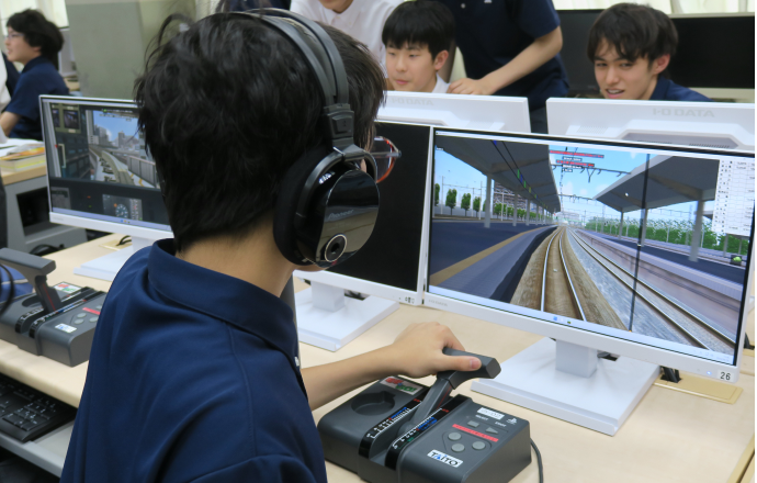 鉄道運転シミュレーター」を操作する高輪中学高等学校旅行・鉄道研究部部員の写真