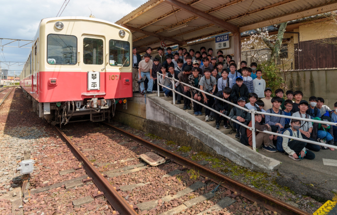 ことでんの車両と高輪中学高等学校旅行・鉄道研究部部員たちの写真