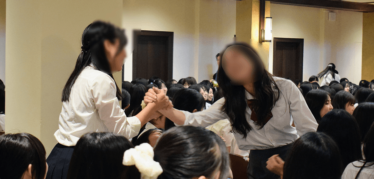 健闘をたたえ手を握り合う立教女学院生徒の写真